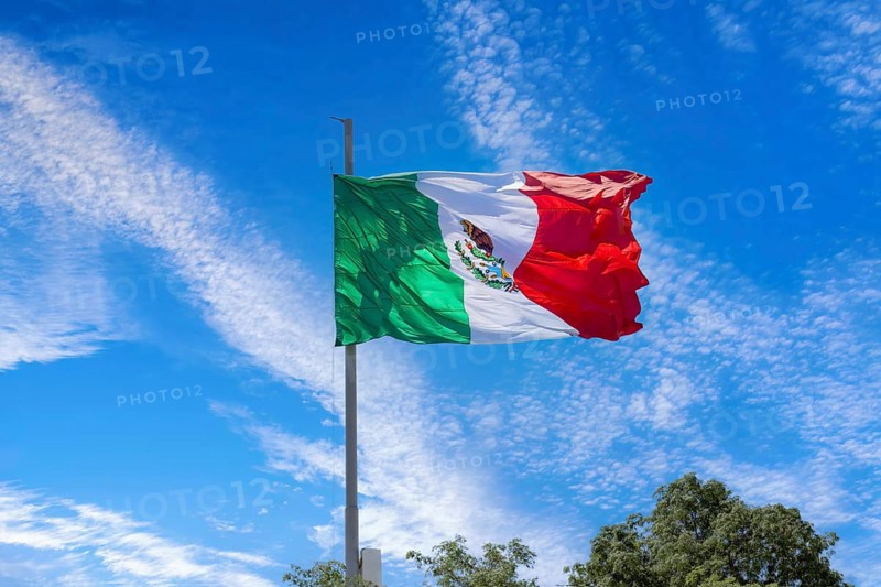 Los Cabos, Mexico, Mexican tricolor national striped flag proudly waving at mast in the air with Aztec symbol for Tenochtitlan, Central America