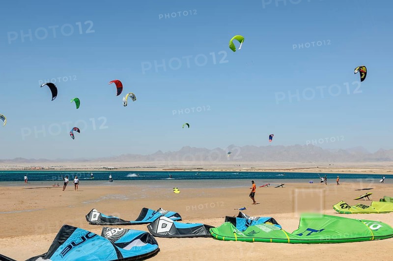 Sailing kitesurfers kite surfers kite surfers on the sea, many kite sails in the blue sky without clouds in the foreground discarded kite sails kite sails lying on sandy beach of Red Sea Bay, Soma Bay, Egypt, Africa