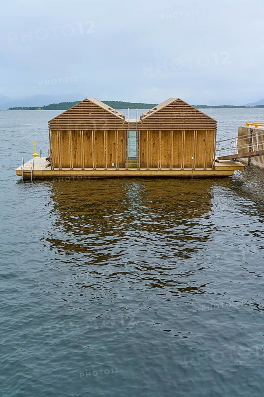 Outdoor sea pool by the fjord with small wooden sauna huts, overcast sky and calm water, Molde, Romsdal, Norway, Europe