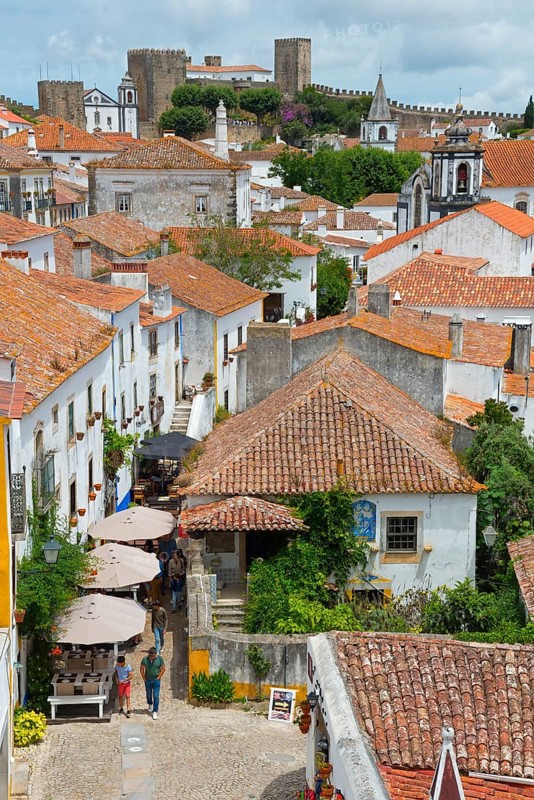 View over a historic town with red roofs and a castle in the background, surrounded by greenery, view from Miradouro Porta, R. Josefa de Óbidos, Óbidos, Obidos, Oeste, Centro, Estremadura, Portugal, Europe