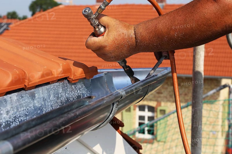 Roofer doing tinsmith work on a gutter