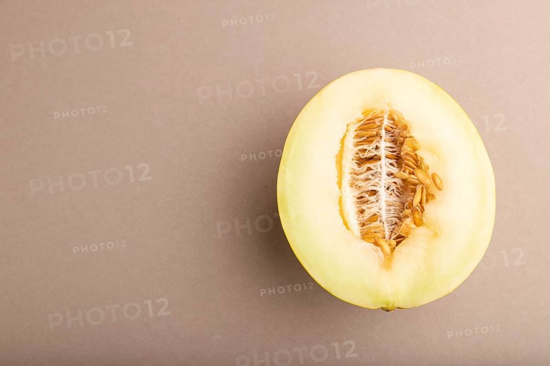 Sliced ripe yellow melon on brown pastel background. Top view, flat lay, copy space. harvest, women health, vegan food, concept, minimalism