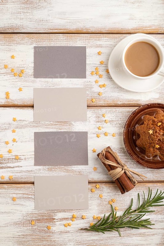 Gray paper business card mockup with cup of coffee and cake on white wooden background. Blank, top view, flat lay, still life