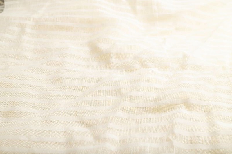 Fragment of smooth white linen tissue. Side view, natural textile background and texture