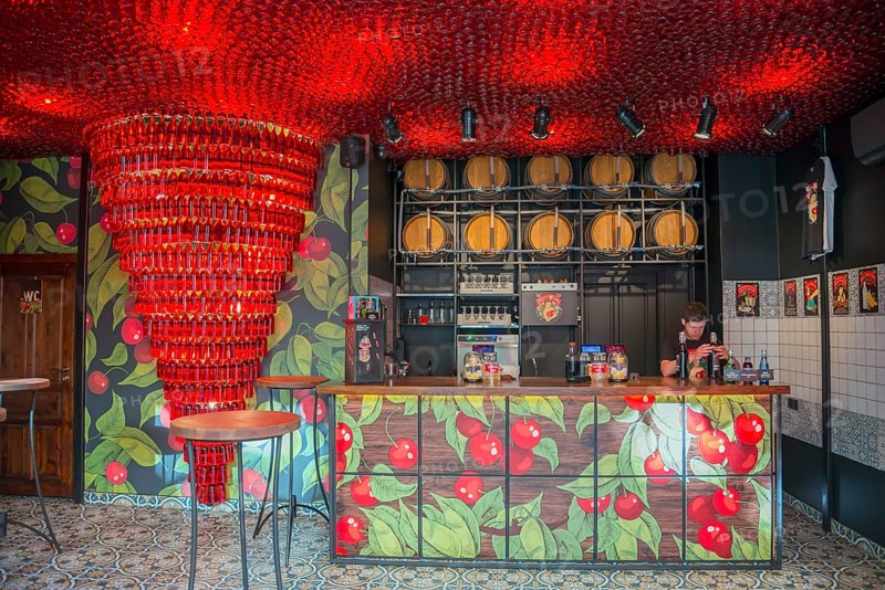 A modern bar with red lighting and barrels in the background, with a bartender behind the counter, Bar Pijana Wisnia, Ukrainian cherry liqueur, Lódz, Lodz, Poland, Europe
