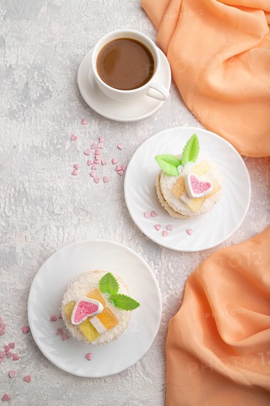 Decorated cake with milk and coconut cream with cup of coffee on a gray concrete background and orange textile. top view, flat lay, close up