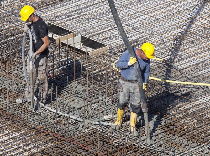 Construction workers backfilling concrete on a building site, Berlin, 19/08/2016