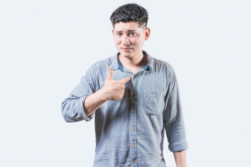 Embarrassed young man pointing at himself isolated. Confused man pointing at himself isolated