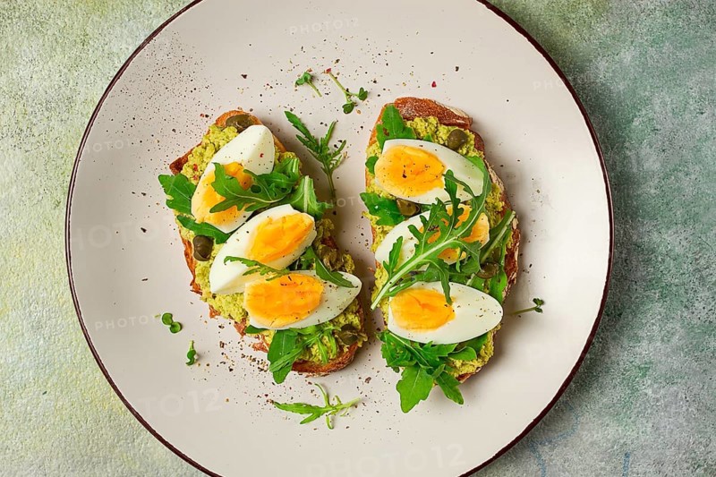Sandwich with mashed avocado, boiled egg, and arugula, on bread, homemade, breakfast