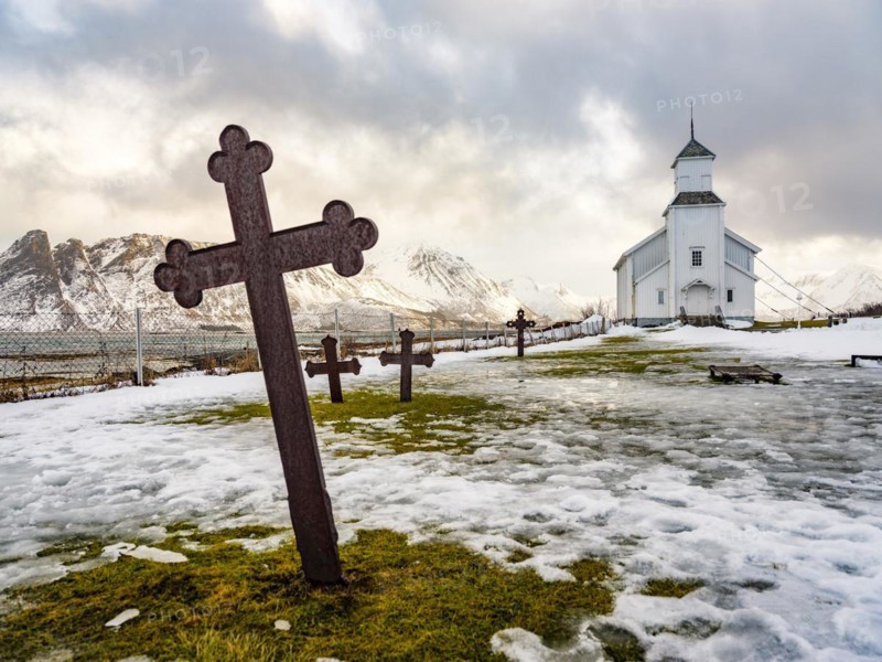 Gimsøy church with cemetery, snow-covered mountains in the background, winter, Gimsøya, Lofoten, Norway, Europe