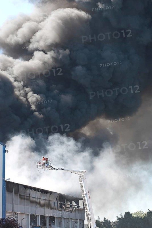 Two firefighters with protective clothing and gas masks in aerial work platform, lifting platform on crane, smoke cloud of a large fire in an industrial building, Lower Saxony, Germany, Europe