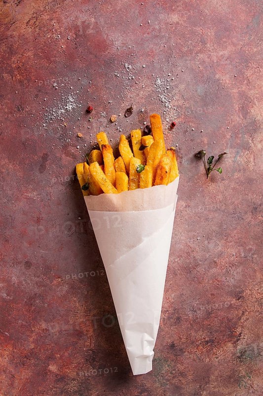 Fried French fries, in a paper bag, on an abstract background, no people, rustic