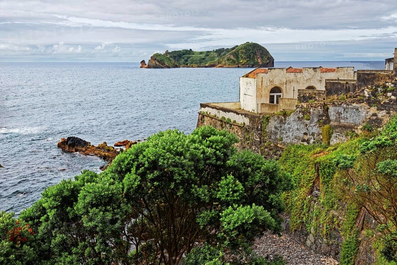 An old ruin on a rocky coast overlooking the sea and the small island and protected area of Ilhéu de Vila Franca do Campoin the distance, small town of Vila Franca do Campo, Sao Miguel, Azores, Portugal, Europe