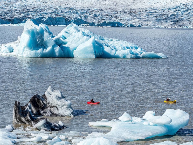 A group of tourists paddles in kayaks between icebergs, glacial lake Fjallsárlón, glacier Fjallsjökull, part of Vatnajökull glacier, Iceland, Europe