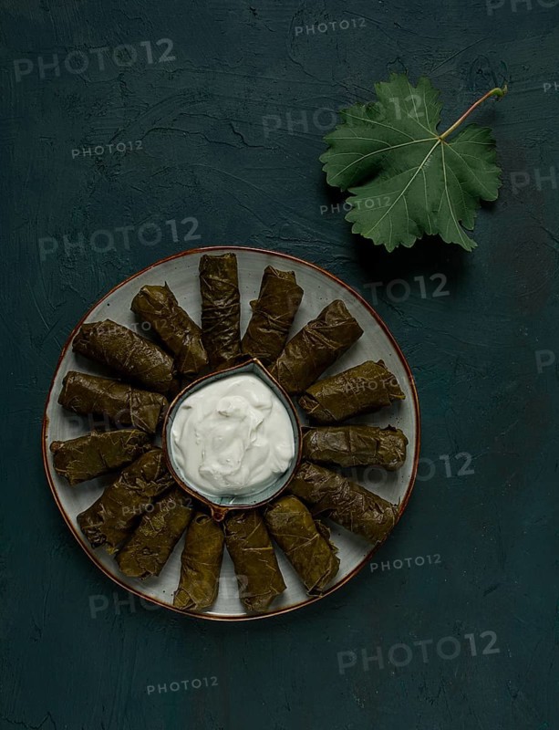 Dolma, cabbage rolls in grape leaves, Traditional Armenian dish, with white sauce, top view, close-up, selective focus