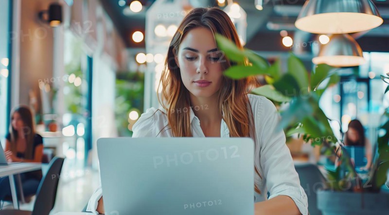 A business woman is sitting at a table with a laptop in front of her working remotely with the team at the cafe, AI generated
