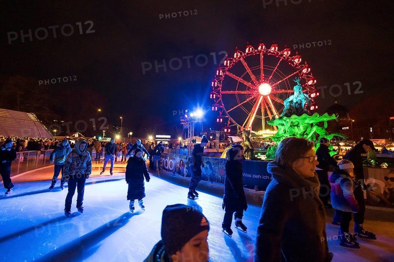 Ice skaters in front of the Neptune Fountain and a Ferris wheel at the Christmas market on Alexanderplatz, Berlin, 21.12.2024
