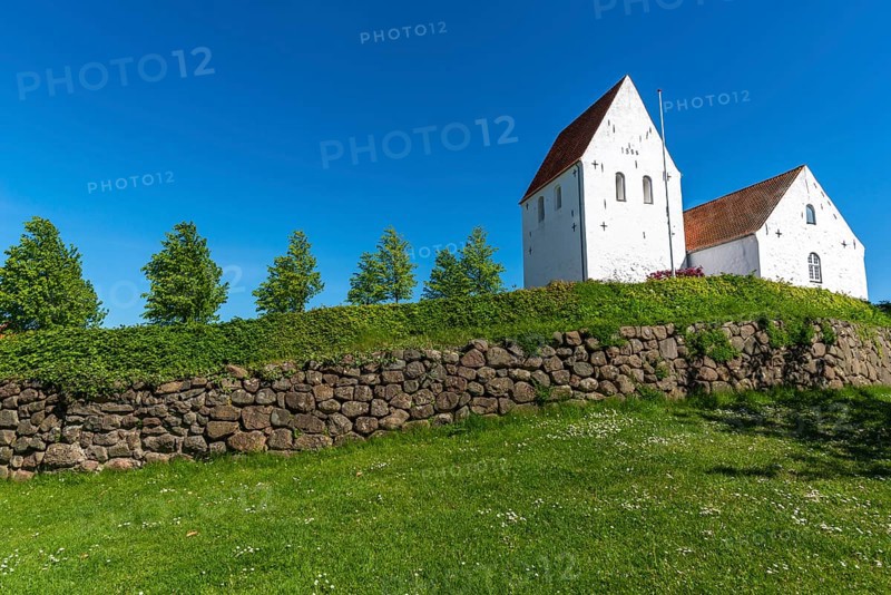 Ulbølle Kirke, whitewashed church on a hill, red roof tiles, group of trees, wall with boulders, Fyn, island of Funen, Denmark, Europe