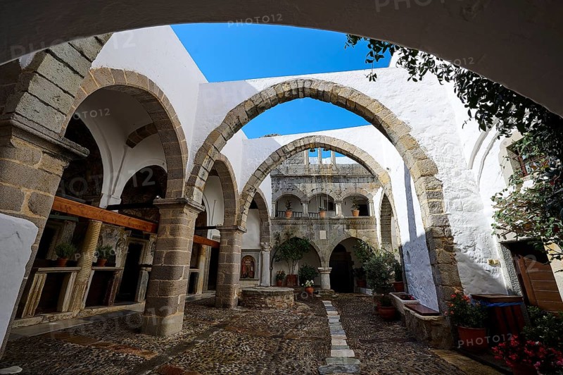Historic courtyard of a monastery with arches and stone structures under a blue sky, Inside the monastery, Agiou Theologou Monastery, Chora, Patmos, Dodecanese, Greek Islands, Greece, Europe