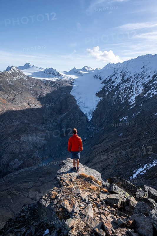 Mountaineer standing on a rock, surrounded by an impressive mountain landscape with snow-covered peaks in autumn View of Gurgler Ferner with summit Hochwilde and Falschungsspitze, Ötztal Alps, Tyrol, Austria, Europe
