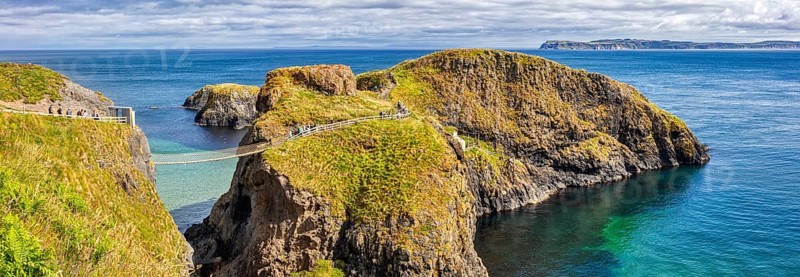 Cliff landscape with bridge and turquoise water under a blue sky, Carrick Bridge