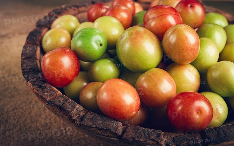 Cherry plum tkemali, fruit, plum variety, in a wooden plate, Georgian cuisine, top view, no people