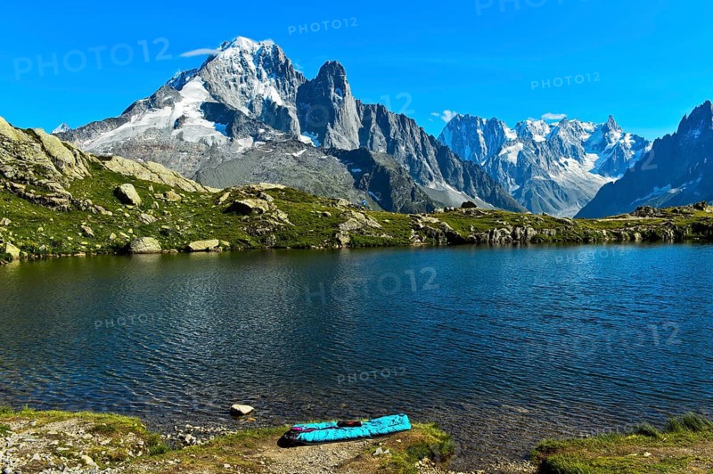 Bivouac site on the shore of the Lacs des Chéserys mountain lake in the Aiguilles Rouges nature reserve, with the Aiguille Verte and Aiguille du Dru peaks behind, Chamonix, Haute Savoie, France, Europe