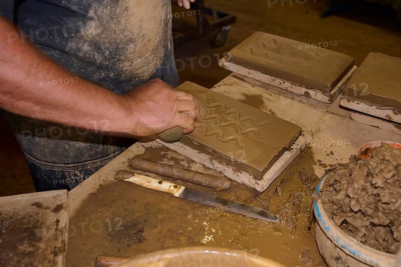 Detailed view of a worker moulding a pattern in a clay brick, surrounded by tools, Patmos Cotto brickworks, Traditional brick making, Kampos, Patmos, Dodecanese, Greek Islands, Greece, Europe
