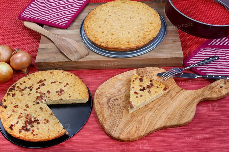 Swabian cuisine, onion tart vegetarian and classic with bacon, baked, savoury, savoury cake, typical Swabian, home cooking, cake tin, from the oven, wooden spatula, cutting board, wooden board, knife, fork, cutlery, potholder, rustic, vegetable onions, traditional cuisine, food photography, studio, Germany, Europe
