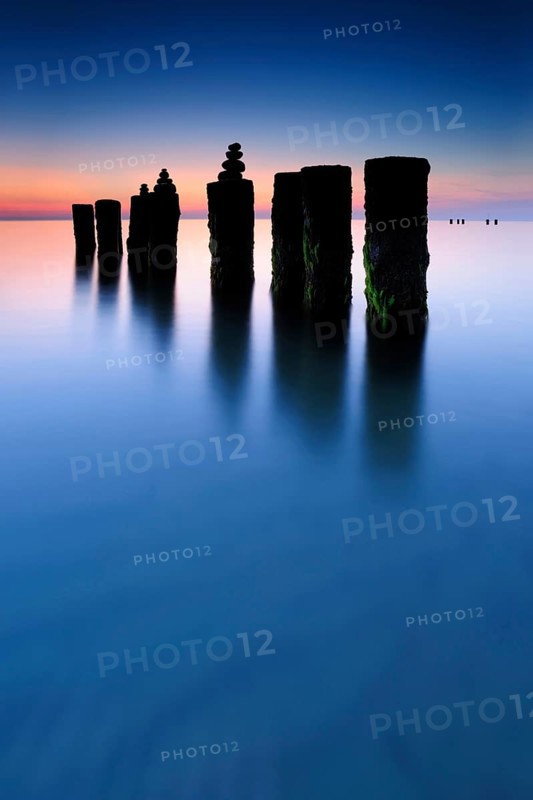 Stone pyramids on old groynes with algae in the water on the beach of the Baltic Sea, long exposure at sunset, Wustrow, Fischland-Darß-Zingst peninsula, Mecklenburg-Vorpommern, Germany, Europe