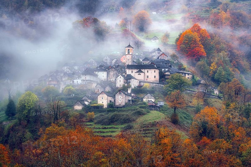 Village view of Corippo in the fog surrounded by autumn-coloured deciduous trees, Verzasca Valley, Canton Ticino, Switzerland, Europe