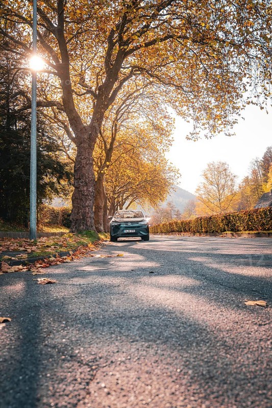 Road in autumn with trees, sunlight and leaves, electric car VW ID5, Deer Carsharing, Gechingen, Black Forest, Germany, Europe