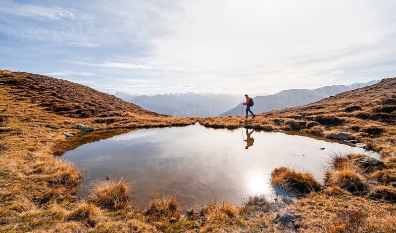 Mountaineer hiking with poles, reflected in a small mountain lake on the Krahberg, mountain panorama in autumn, Venet crossing, Ötztal Alps, Tyrol, Austria, Europe