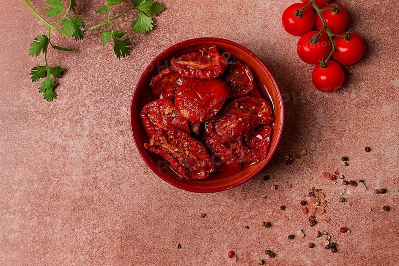 Dried tomatoes, in a bowl, top view, on a brown background