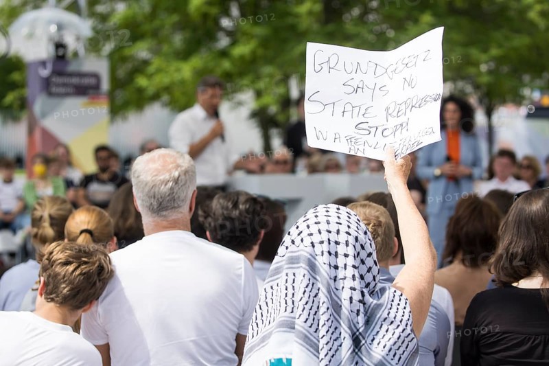 A visitor with a Palestinian scarf holds a piece of paper with the inscription Grundgesetz Says No State Repression / Stop arms deliveries to Israel at the dialogue format with Robert Habeck (Vice-Chancellor and Federal Minister for Economic Affairs and Climate Protection, The Greens) on the topic: What it's all about: Protecting freedom and democracy, renewing prosperity in the dialogue forum at Demokratie feiern. / The Basic Law turns 75, together it will be a celebration, Berlin, 25.05.2024