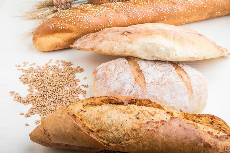 Different kinds of fresh baked bread on a white wooden background. side view, close up