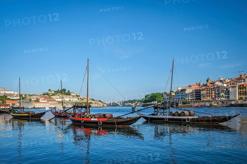 View of Porto city and Douro river with traditional boats with port wine barrels from famous tourist viewpoint Marginal de Gaia riverfront. Porto, Vila Nova de Gaia, Portugal, Europe