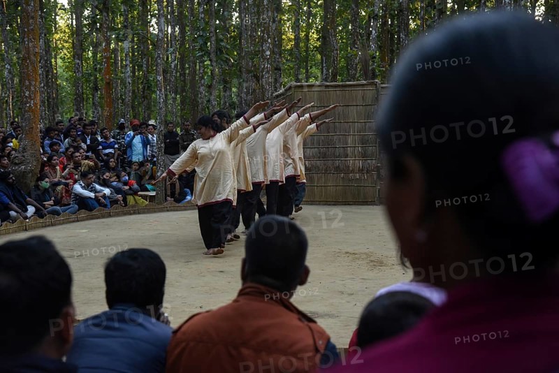 People enjoying a drama during 'Under The Sal Tree' Theatre Festival on December 15, 2021 in Goalpara, Assam, India. Under the Sal Tree theatre festival is one of its kind, held at Badungduppa Kala Kendra in the middle of a dense Sal forest in rural Lower Assam. The festival was started by Sukracharjya Rabha, a widely respected theatre personality of Assam, in 2008. He wanted to spread a message of coexistence with nature and made in a completely natural setting inside a jungle, which made the theatre festival unique