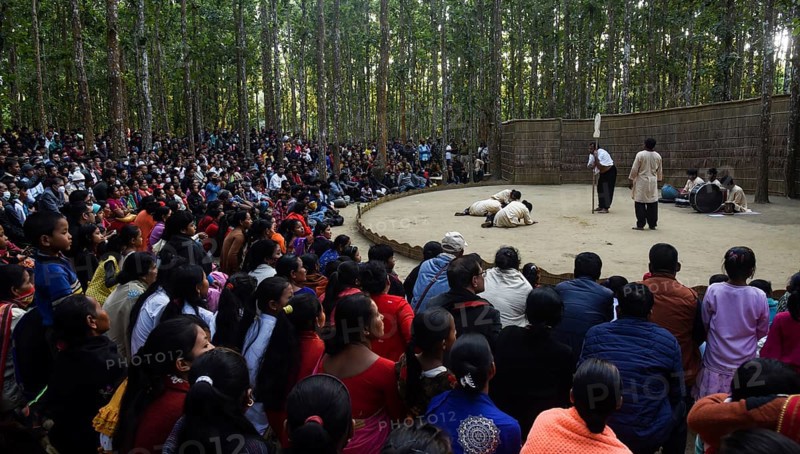 People enjoying a drama during 'Under The Sal Tree' Theatre Festival on December 15, 2021 in Goalpara, Assam, India. Under the Sal Tree theatre festival is one of its kind, held at Badungduppa Kala Kendra in the middle of a dense Sal forest in rural Lower Assam. The festival was started by Sukracharjya Rabha, a widely respected theatre personality of Assam, in 2008. He wanted to spread a message of coexistence with nature and made in a completely natural setting inside a jungle, which made the theatre festival unique