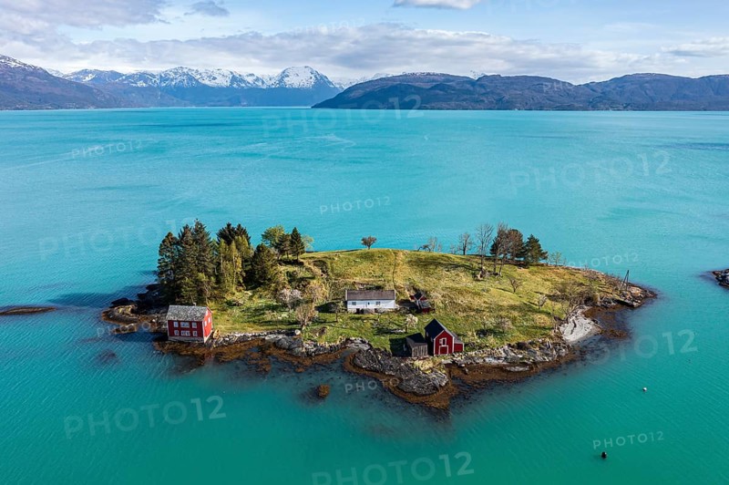 Aerial view of typical red houses on an island in the Hardangerfjord, mountain range in the back, near Strandebarm, Hordaland, Norway, Europe