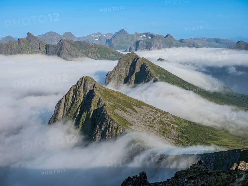View over cloud covered mountain range at Mt. Husfjell, view towards fjord Bergsfjorden, Senja island, Norway, Europe