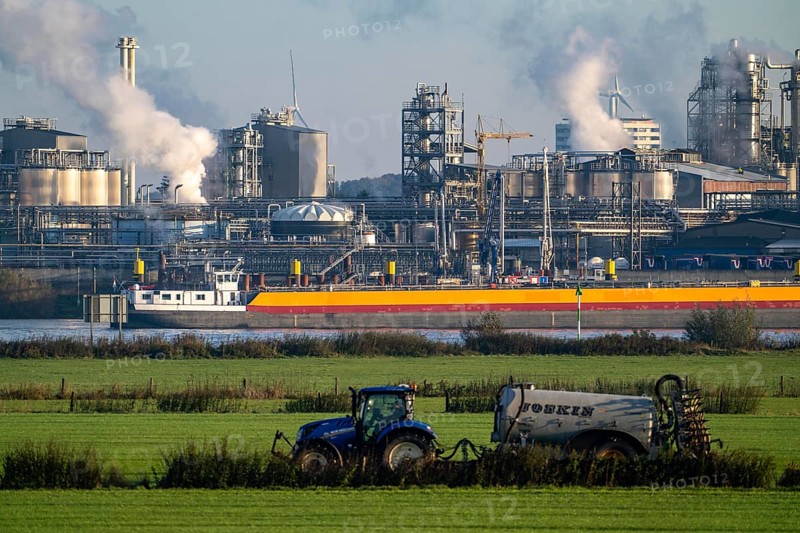 Cargo ship on the Rhine near Emmerich, Kao Chemicals backdrop, specialising in surfactants, KLK, Left Rhine pastures, tractor, slurry application, Lower Rhine, North Rhine-Westphalia, Germany, Europe