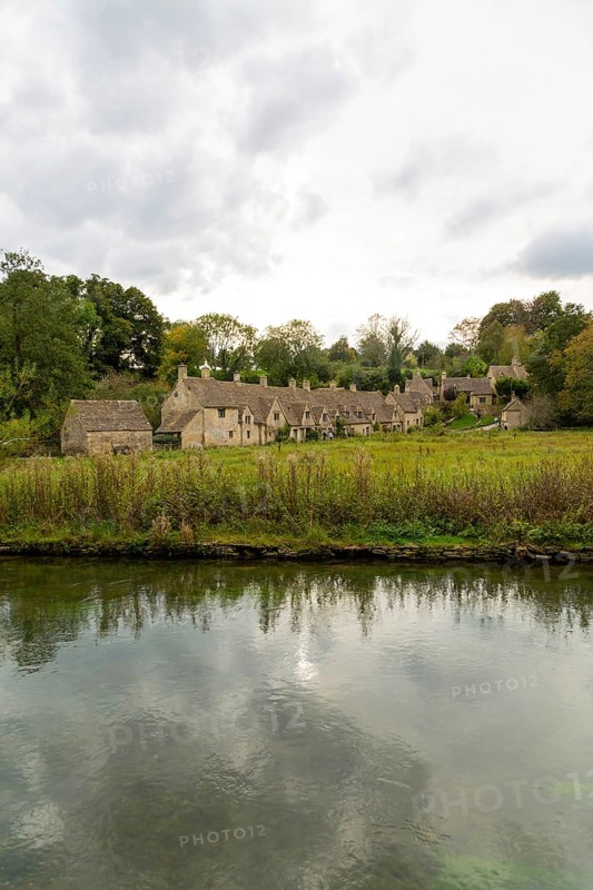 Famous Cotswold buildings at Arlington Row viewed from River Colne, Bibury, Gloucestershire, England, UK