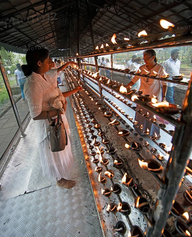 Sri Lankan pilgrims pour oil into candle holders at the Buddhist Temple of the Tooth or Sri Dalada Maligawa, Kandy, Central Province, Sri Lanka, Asia