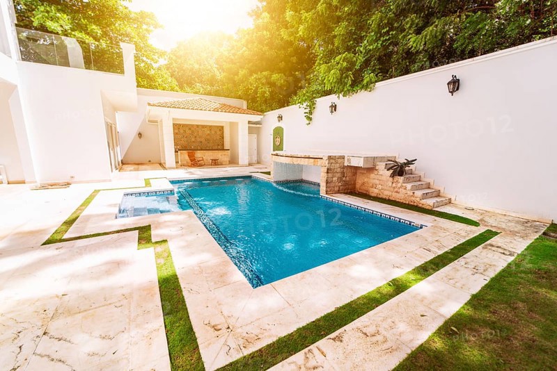 Homemade swimming pool surrounded by trees. Beautiful crystal clear swimming pool in a backyard. Concept of domestic swimming pool designs