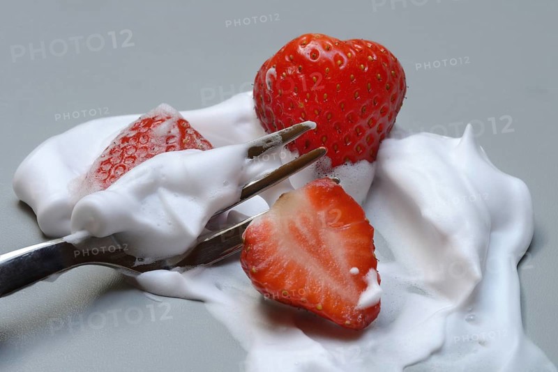 Strawberries on a fork with whipped cream