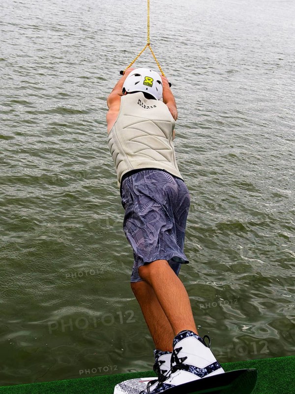Young man with wakeboard at the jump start, water sports in the wakepark
