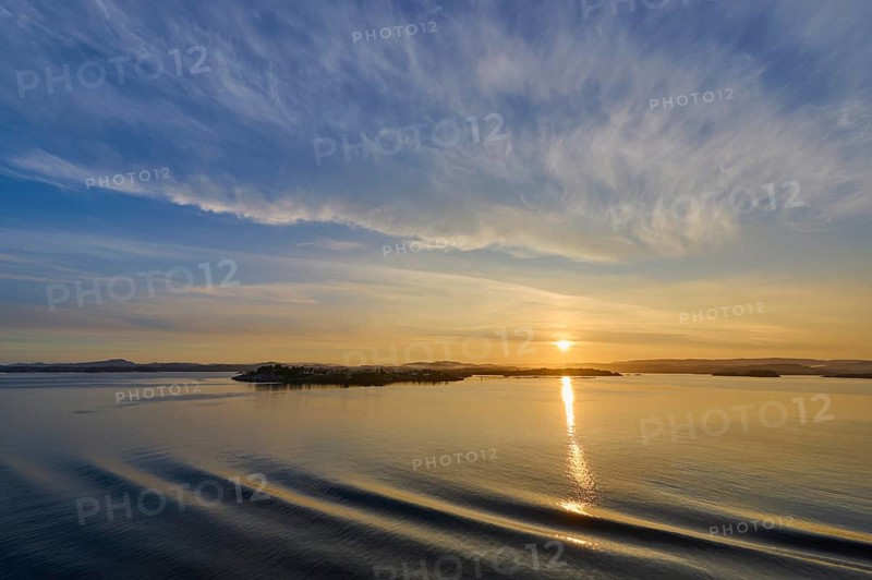Calm seascape at sunrise with soft clouds and island in the background, Bergen, Vestland, Norway, Europe