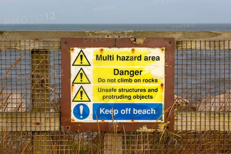 Environment Agency warning danger sign above rock armour, East Lane, Bawdsey, Suffolk, England, UK