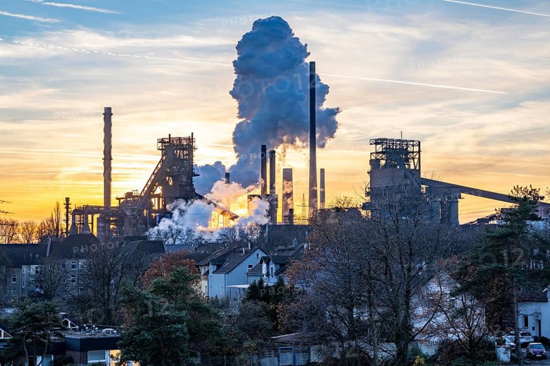 Blast furnace Schwelgern 1, Black Giant, Schwelgern 2 ThyssenKrupp Steel plant Schwelgern in Duisburg-Marxloh is part of the Bruckhausen steelworks, residential buildings in the Marxloh district, extinguishing cloud from the Schwelgern coking plant, sunset, North Rhine-Westphalia, Germany, Europe
